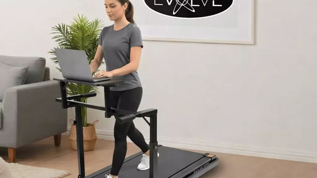 A person walks on a treadmill with a laptop on a desk.